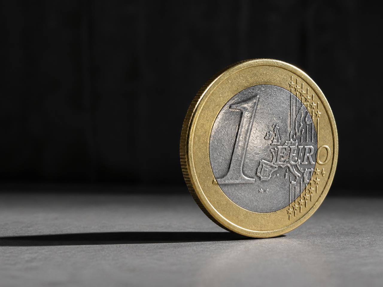 Eine aufrecht stehende 1-Euro-Münze im Seitenlicht
